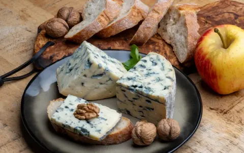 Kawałki sera gorgonzola z niebieską pleśnią, podane z chlebem, orzechami i jabłkiem. Idealne na przekąskę, która odpowie na pytanie: co to gorgonzola.