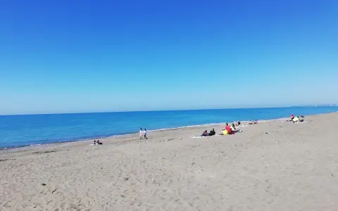 Słoneczny dzień na plaży w Marina di Bibbona. Ludzie odpoczywają na piasku, a morze lśni w słońcu.