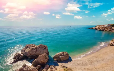 Piękne wybrzeże Costa del Sol z białymi domkami na klifie, turkusowym morzem i skalistą plażą. Idealne miejsce na wakacje!