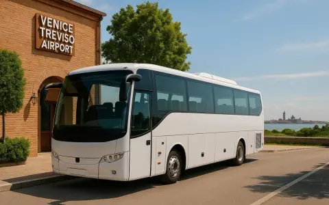 Biały autokar czeka na pasażerów przy budynku z napisem VENICE TREVISO AIRPORT. W tle widać panoramę Wenecji.