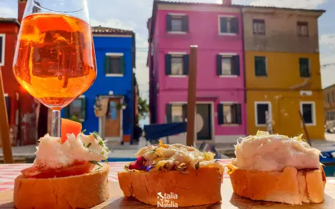 Co zjeść w Wenecji? Aperol i bruschetty na tle kolorowych domów Burano. Idealne połączenie smaków i widoków.