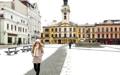 Zimowy spacer po Rynku w Cieszynie. Kobieta w ciepłym ubraniu przemierza ośnieżony plac, podziwiając zabytkowe kamienice i ratusz. Idealny pomysł na cieszyn w jeden dzień.
