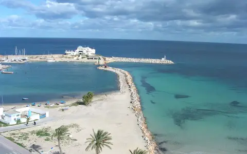 Piękna pogoda w Tunezji w październiku. Błękitne morze, biała plaża i palmy tworzą rajski krajobraz.
