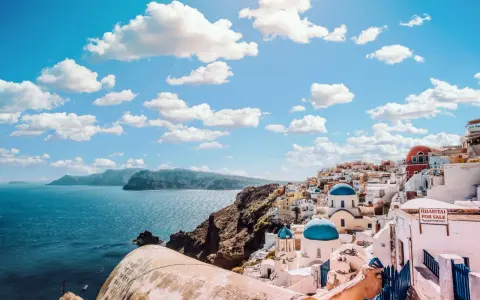 Santorini, Grecja. W jakim języku mówi się w Grecji? Po grecku! Białe domy, niebieskie kopuły i morze.