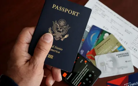 Dłoń trzyma paszport USA. Obok leżą karty kredytowe, bilet lotniczy i telefon. To wszystko, co potrzebne, by wiedzieć, esta jak wypełnić.