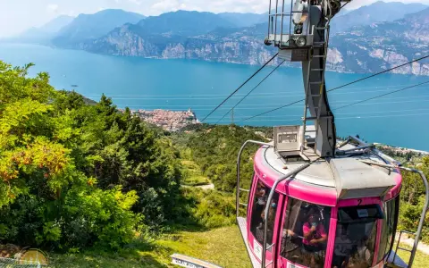 Różowa kolejka linowa Monte Baldo zjeżdża w dół, oferując widok na jezioro Garda i malownicze miasteczko.