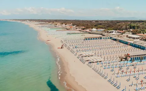 Widok z lotu ptaka na plażę w Marina di Cecina, Toskania, z rzędami leżaków i parasoli.