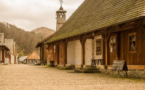 Drewniana zabudowa skansenu, wieża z wiatrowskazem i tablica "Pamiątki Regionalne" - tak z czego słynie Sanok.