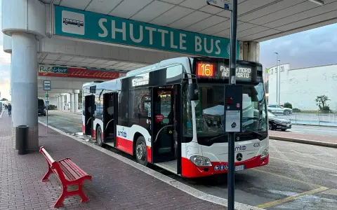 Autobus wahadłowy z lotniska do centrum miasta, z otwartymi drzwiami, gotowy do odjazdu.