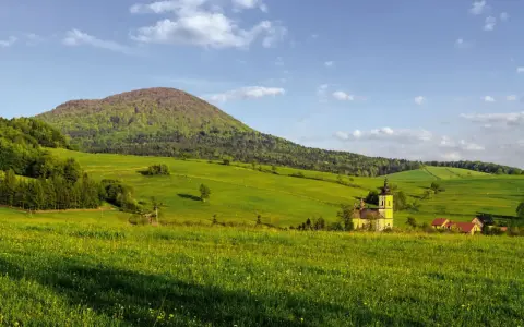 Zielone wzgórza Beskidu Niskiego z kościołem i górą Lackowa w tle.