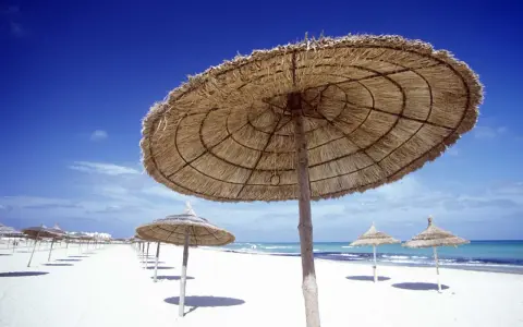 Słomiane parasole na pustej plaży w Tunezji. Marzec zapowiada piękną pogodę i spokojne morze.