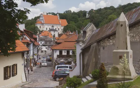 Widok na urokliwą, brukowaną uliczkę Kazimierza Dolnego z zabytkową architekturą i kościołem w tle.