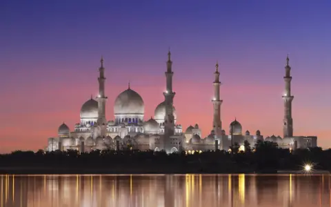 Wspaniały meczet oświetlony nocą, odbijający się w wodzie. Idealny widok, kiedy jest Ramadan.