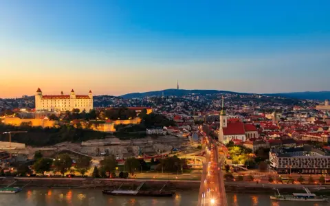 Widok na Bratysławę o zachodzie słońca z zamkiem i mostem nad Dunajem.
