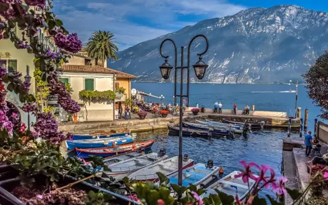 Malowniczy port z łodziami, budynkami i górami w tle nad Jeziorem Garda.