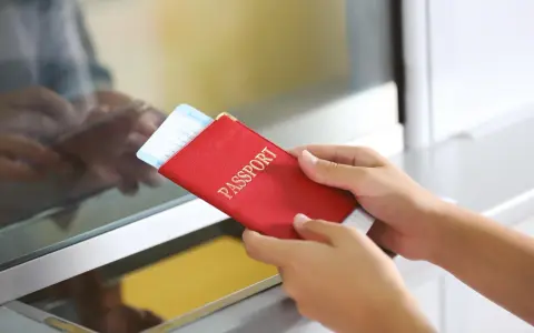 Ręce trzymają czerwony paszport z biletem lotniczym. Pamiętaj, czego nie wolno wywozić z Sycylii, by uniknąć problemów.