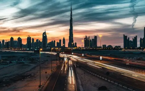 Wieczorny widok na Dubaj z Burj Khalifa, gdzie światła samochodów tworzą smugi na autostradzie. Ciekawostki o tym drapaczu chmur mogą dotyczyć jego wysokości i budowy.