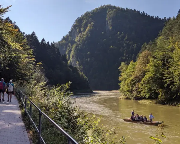 Ścieżka pieszo-rowerowa nad Dunajcem, w tle góry i tratwa.