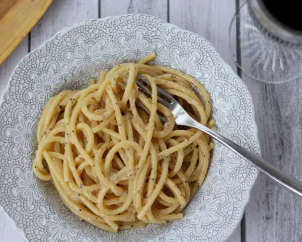 Porcja kremowego spaghetti cacio e pepe z widelcem, gotowa do zjedzenia.