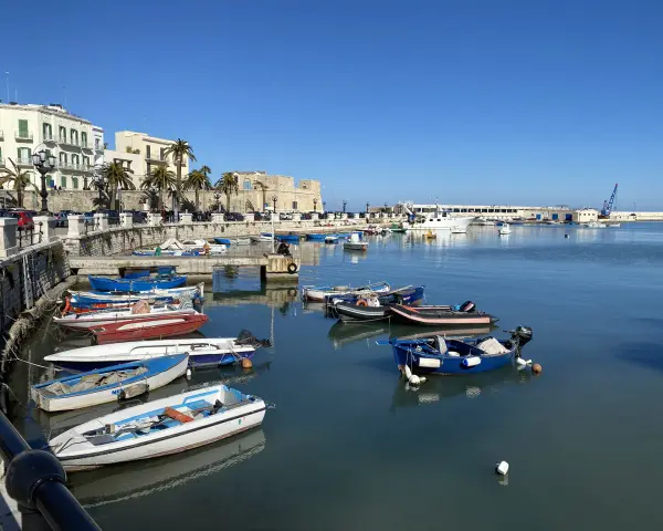 Widok na port w Bari z łodziami i budynkami w tle.