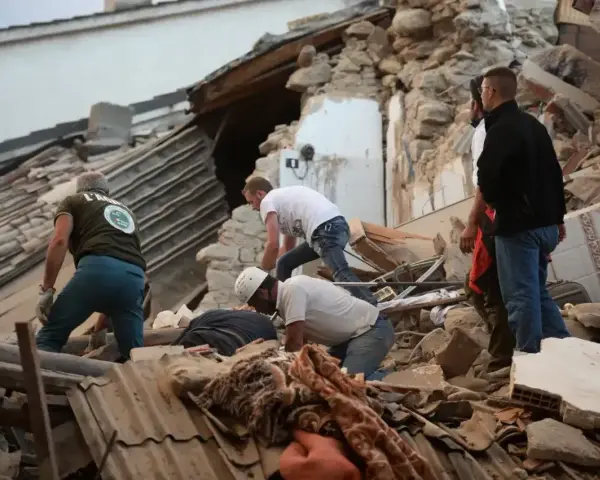 Ratownicy przeszukują gruzy po trzęsieniu ziemi we Włoszech. Zniszczone budynki i chaos po katastrofie.