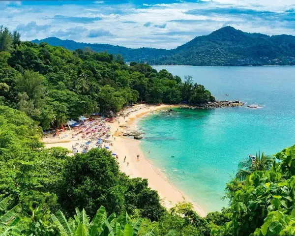 Tropikalna plaża z turkusową wodą, zielonymi wzgórzami i leżakami.
