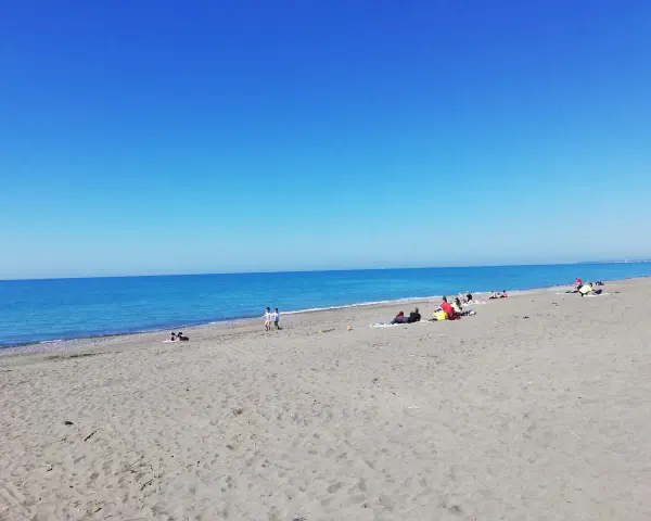 Słoneczny dzień na plaży w Marina di Bibbona. Ludzie odpoczywają na piasku, a morze lśni w słońcu.