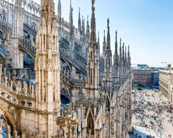Majestatyczne iglice katedry Duomo w Mediolanie w listopadzie, z widokiem na tętniący życiem plac poniżej.