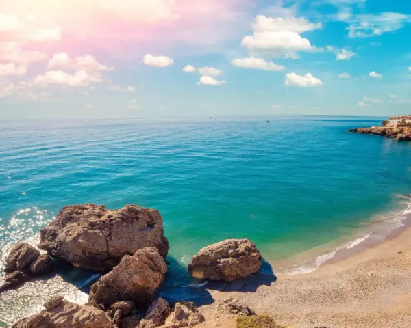 Piękne wybrzeże Costa del Sol z białymi domkami na klifie, turkusowym morzem i skalistą plażą. Idealne miejsce na wakacje!