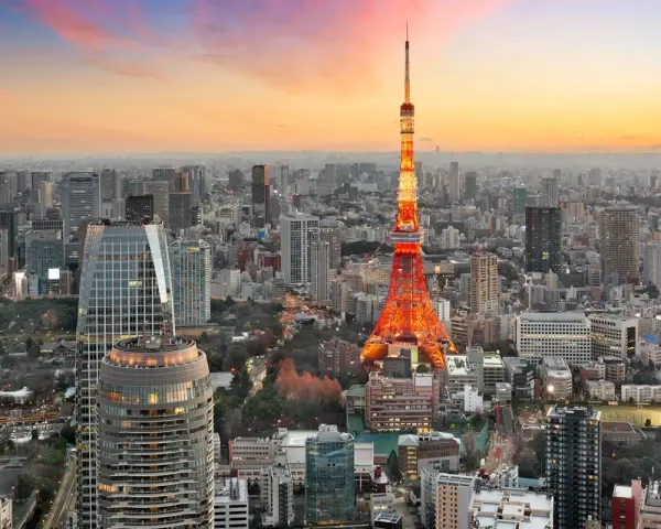 Widok na Tokio, jedno z 10 największych miast na świecie, z wieżą Tokyo Tower w pomarańczowych barwach o zachodzie słońca.