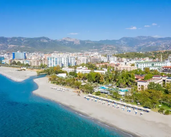 Widok z lotu ptaka na kurort nad morzem w Turcji z plażą, hotelami i górami w tle.
