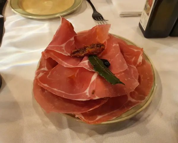 Plastry prosciutto na talerzu, idealne na przystawkę we Florencji. Co zjeść? Prosciutto to świetny wybór!