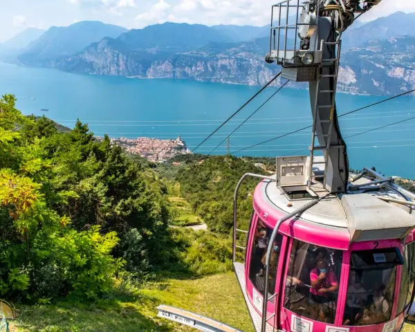 Różowa kolejka linowa Monte Baldo zjeżdża w dół, oferując widok na jezioro Garda i malownicze miasteczko.