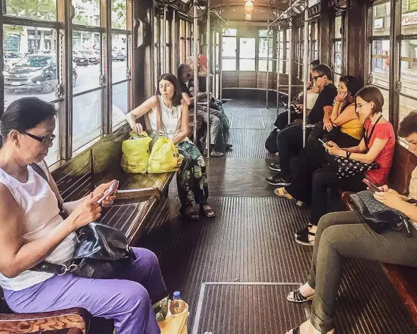 Wnętrze tramwaju w Mediolanie. Pasażerowie korzystają z mediolańskiej komunikacji miejskiej, przeglądając telefony.