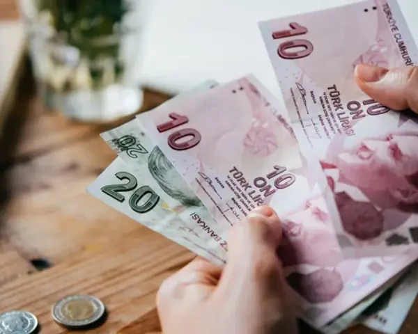 Ręka trzyma banknoty 10 i 20 lir tureckich. To pokazuje, czym płacić w Turcji.