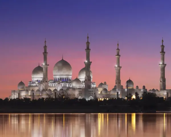 Wspaniały meczet oświetlony nocą, odbijający się w wodzie. Idealny widok, kiedy jest Ramadan.