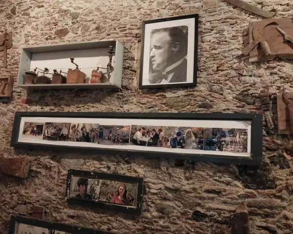 Pamiątki z miejsc, gdzie kręcono Ojca Chrzestnego: portret Marlona Brando, kolaż scen z filmu i stare młynki do kawy.