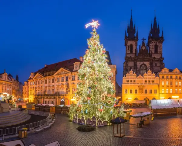 Jarmark bożonarodzeniowy w Pradze. Ogromna, oświetlona choinka na Rynku Staromiejskim, w tle gotycka architektura i zabytkowe kamienice.