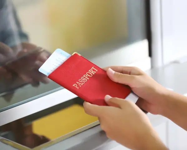 Ręce trzymają czerwony paszport z biletem lotniczym. Pamiętaj, czego nie wolno wywozić z Sycylii, by uniknąć problemów.