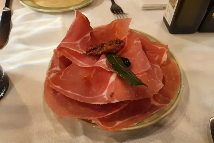 Plastry prosciutto na talerzu, idealne na przystawkę we Florencji. Co zjeść? Prosciutto to świetny wybór!