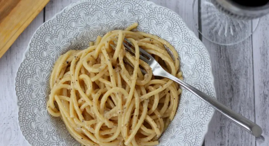 Porcja kremowego spaghetti cacio e pepe z widelcem, gotowa do zjedzenia.