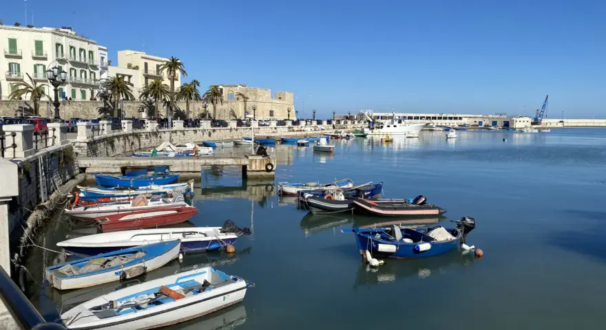 Widok na port w Bari z łodziami i budynkami w tle.