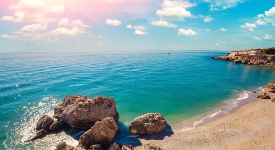 Piękne wybrzeże Costa del Sol z białymi domkami na klifie, turkusowym morzem i skalistą plażą. Idealne miejsce na wakacje!