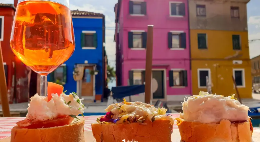 Co zjeść w Wenecji? Aperol i bruschetty na tle kolorowych domów Burano. Idealne połączenie smaków i widoków.