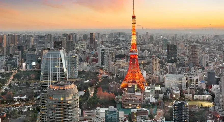 Widok na Tokio, jedno z 10 największych miast na świecie, z wieżą Tokyo Tower w pomarańczowych barwach o zachodzie słońca.