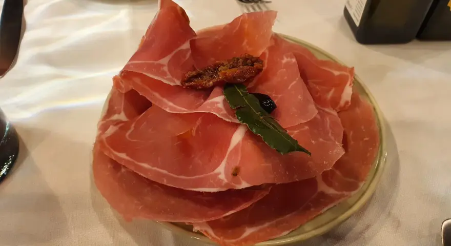 Plastry prosciutto na talerzu, idealne na przystawkę we Florencji. Co zjeść? Prosciutto to świetny wybór!