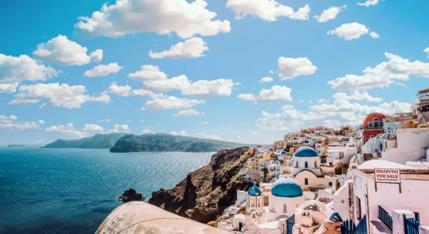 Santorini, Grecja. W jakim języku mówi się w Grecji? Po grecku! Białe domy, niebieskie kopuły i morze.