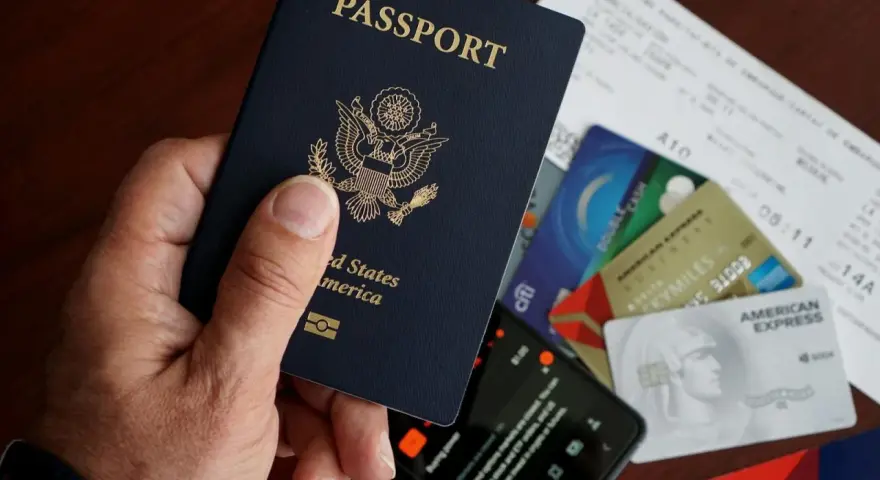 Dłoń trzyma paszport USA. Obok leżą karty kredytowe, bilet lotniczy i telefon. To wszystko, co potrzebne, by wiedzieć, esta jak wypełnić.