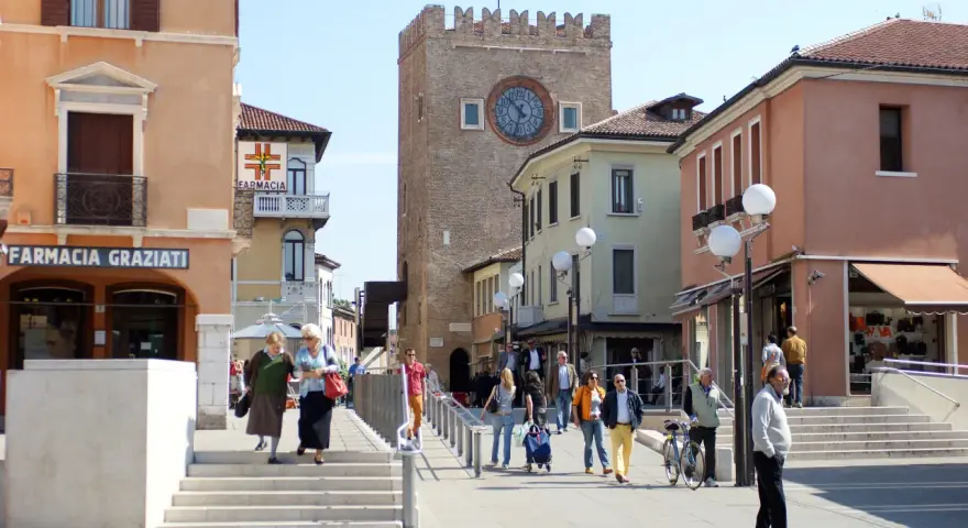 Rynek w Mestre z wieżą zegarową i ludźmi spacerującymi po placu.