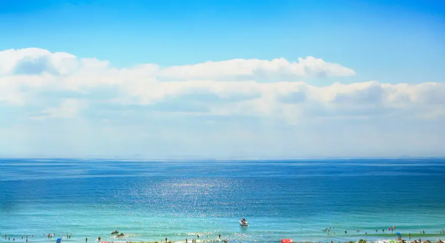 Słoneczna plaża w Bułgarii, idealna na wrzesień. Temperatura wody i powietrza zachęca do kąpieli i relaksu pod parasolami.